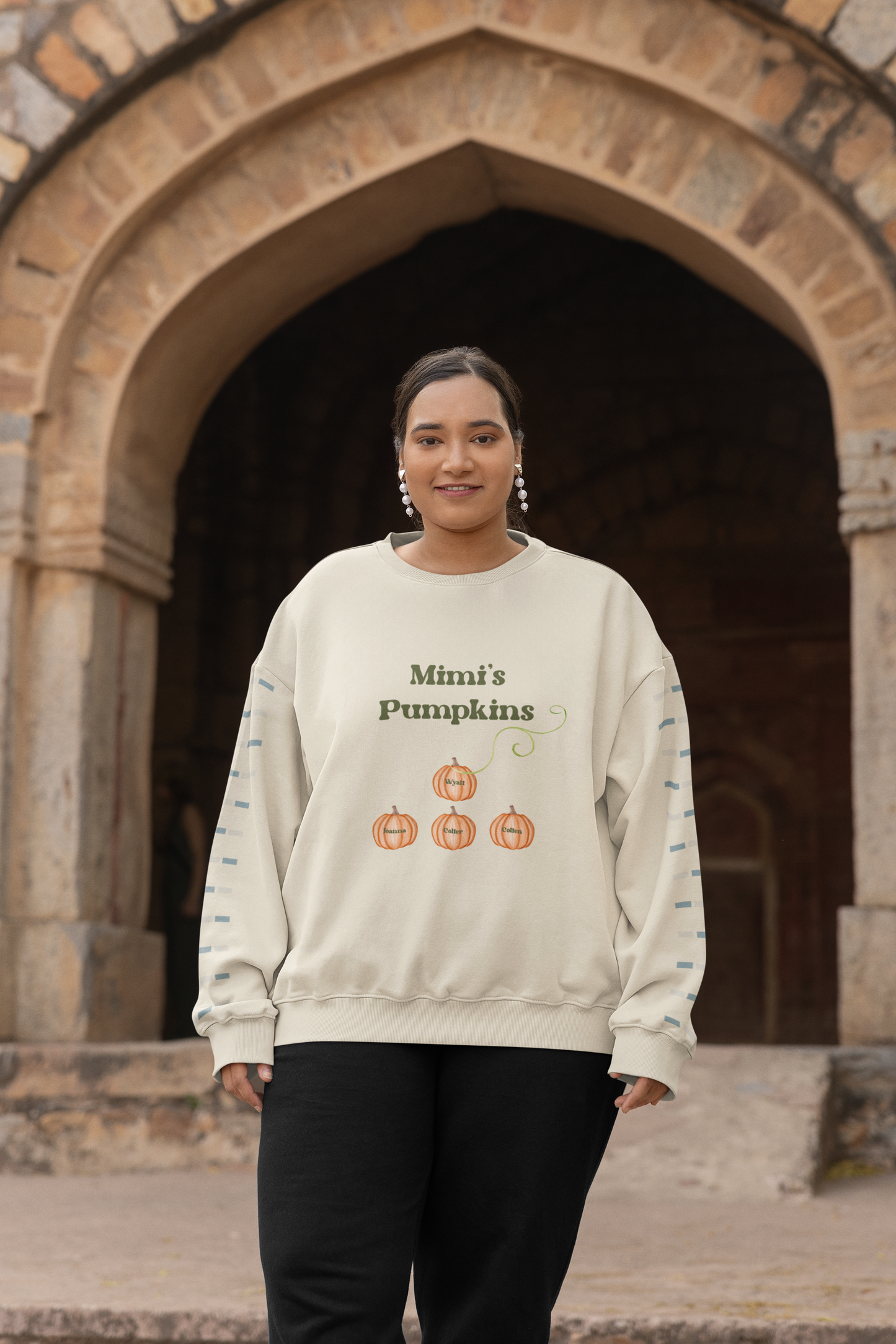 Woman in cream custom Mama’s Pumpkins sweatshirt with pumpkin graphic and long sleeves worn as fall casual outfit