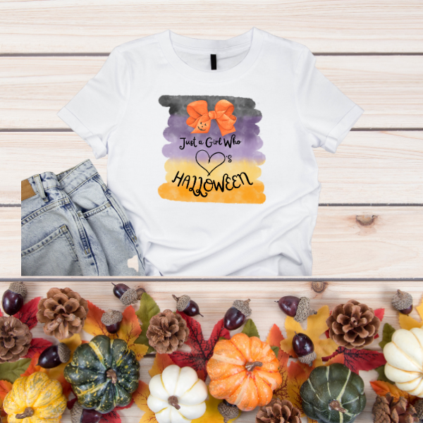 White womens tee with watercolor black purple orange stripes, pumpkin bow graphic and text Just a Girl Halloween t-shirt