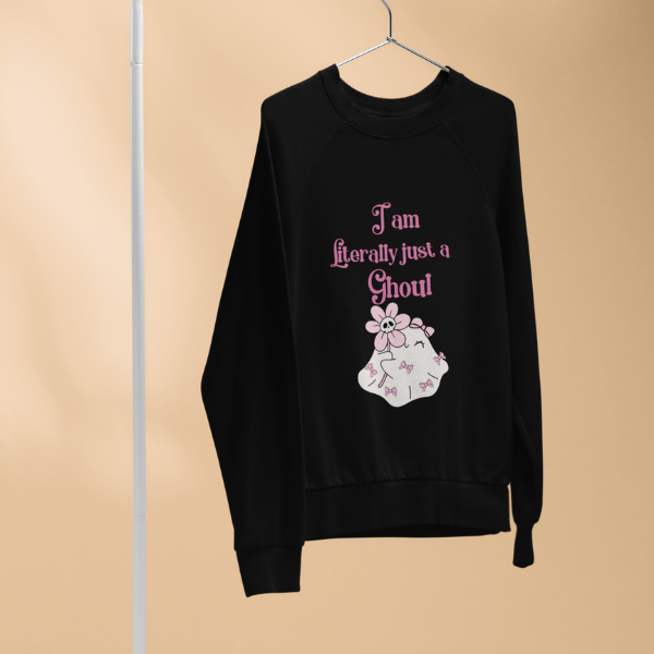Black sweatshirt hanging on hanger with pink ghost graphic and text reading I'm literally just a ghoul sweatshirt.